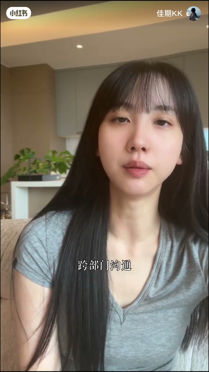 佳期KK灰 V 领短袖出镜，居家浅柜与绿植背景；底部白字字幕「跨部门沟通」；开场把会议、汇报、群消息、跨部门沟通定性为「立场」